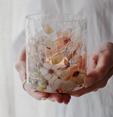 Bild på ljuslykta med blommor och fjärilar i sprucket glas