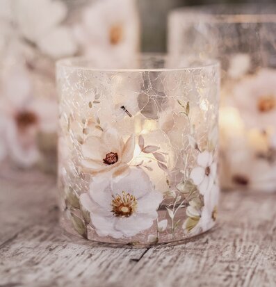 Bild av ljuslykta med blommor och fjärilar på sprucket glas