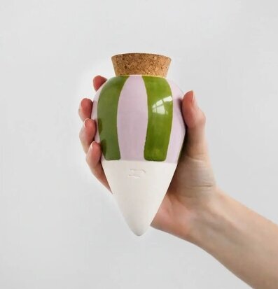 Bild på hand som håller färgglad bevattningsprodukt i keramik