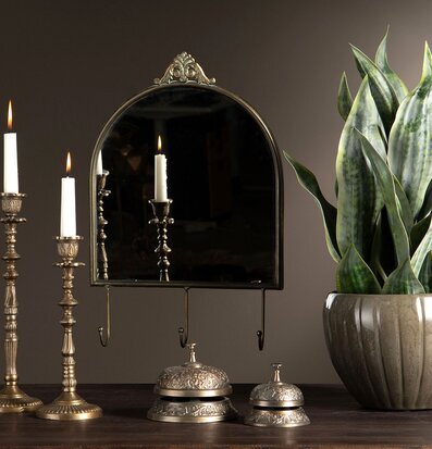 Bild av tidlöst stilleben med spegel, ljusstakar och grönväxt