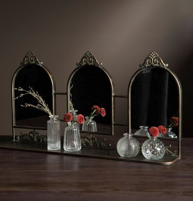 Bild på elegant tredelad spegel med glasvaser och växter
