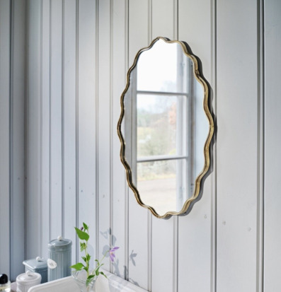 Bild på badrum med vågig spegel och klassisk panelvägg