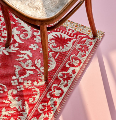 Bild av färgstark plastmatta och trästol i soligt rum