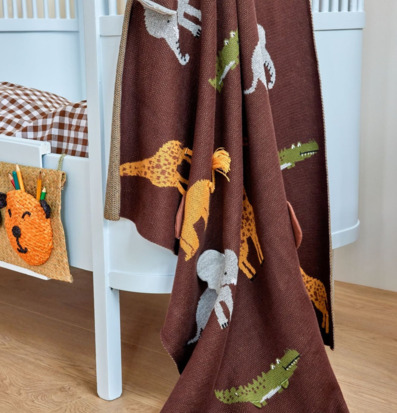 Bild på barnfilt med djurmotiv och mjuka färger i barnrum