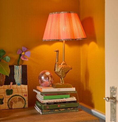 Bild av färgstarkt stilleben med lampa och böcker i gult rum