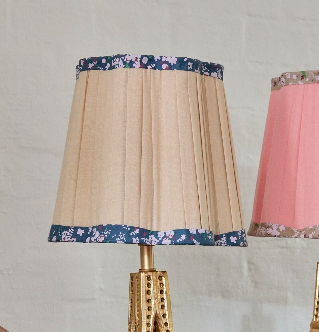 Bild på lampskärm i sandfärg med blå blomsterbård och mässing