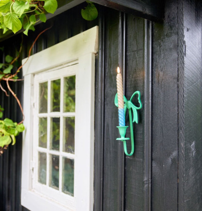 Bild av svart träfasad med grön ljusstake och gröna växter