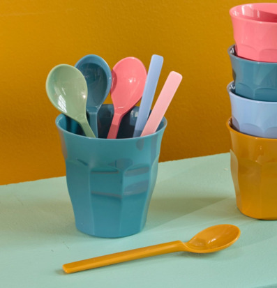 Bild av färgglada plastglas och teskedar i lekfull miljö