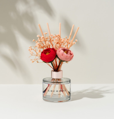 Bild av doftpinnar med rosa och röda blommor i glasbehållare