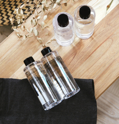 Bild på eleganta refillflaskor med rosdoft på träbord