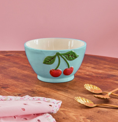 Bild av keramikskål i mintblått med körsbär på träbord