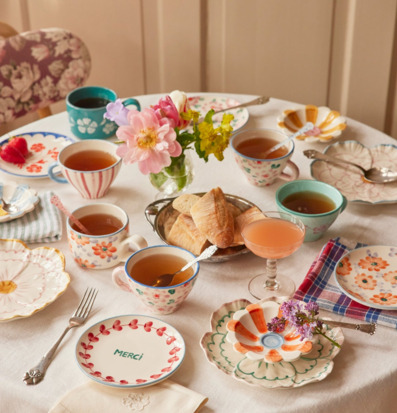 Bild av dukat bord med färgglatt porslin och fika i vårsol