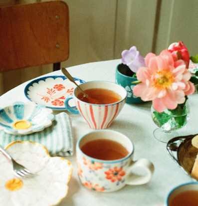 Bild av ljust dukat bord med färgglad keramik och blommor
