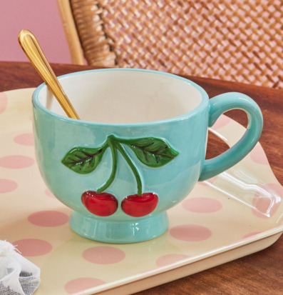 Bild av keramikkopp med körsbär på mintgrönt fat och träbord