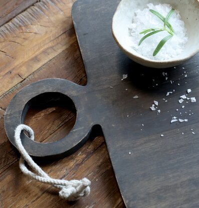 Bild på grå träbricka med keramikskål, salt och örtkvist