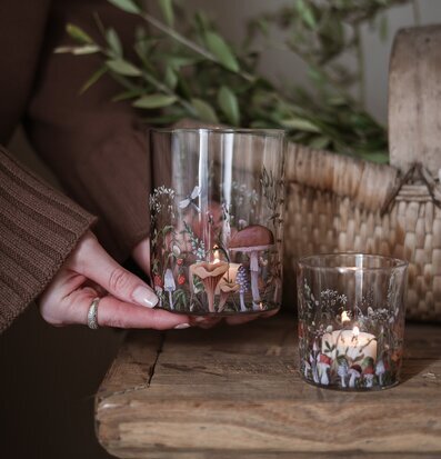 Bild av ljuslyktor med skogsmotiv på rustikt träbord och korg