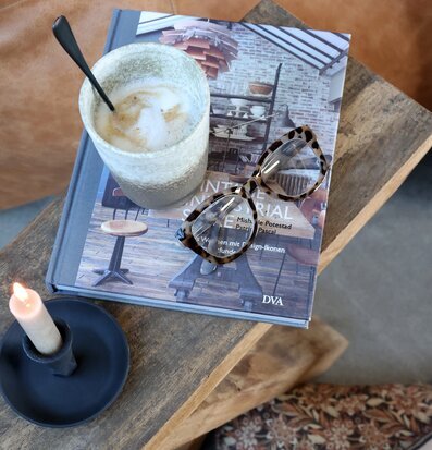 Bild av sidobord i naturnära vardagsmiljö med bok och kaffe