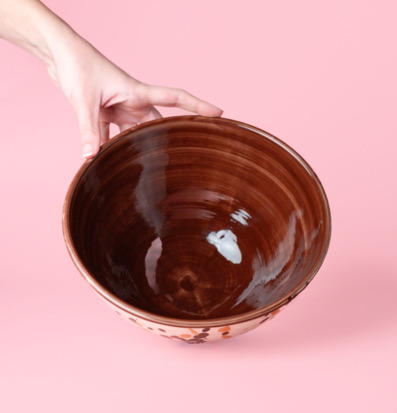 Bild av handgjord keramikskål med prickar mot rosa bakgrund