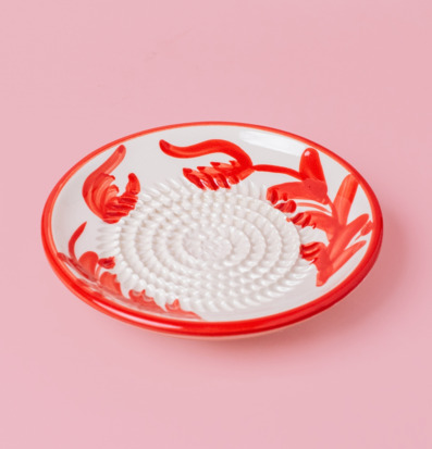 Bild av keramisk rivplatta med rött handmålat växtmönster