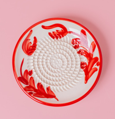 Bild av handgjord keramisk rivplatta med röd dekor och glans