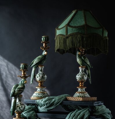 Bild på grön lampskärm och papegojljusstakar i stilleben