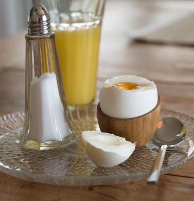 Bild av frukost med äggkopp i teak, glas och apelsinjuice