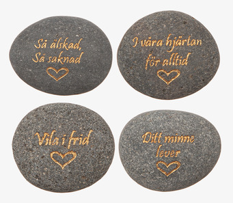 Bild på fyra grå minnesstenar med guldfärgad text och hjärta
