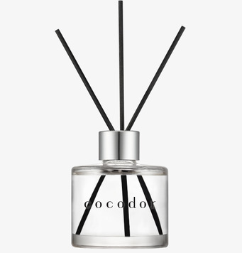 Bild på eleganta doftpinnar i glasflaska med vit bakgrund