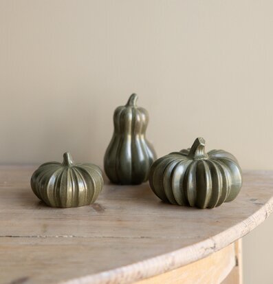 Bild med gröna keramikkannor formade som pumpor på träbord