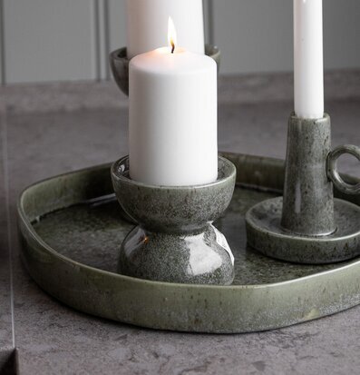 Bild på gröna ljusstakar i keramik på grå bänkskiva