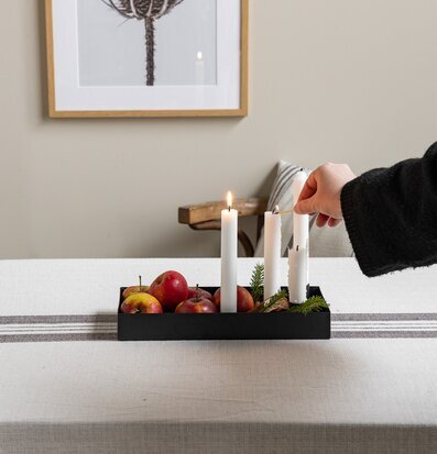 Bild av harmonisk bordsdekoration med svart ljusstake och äpplen