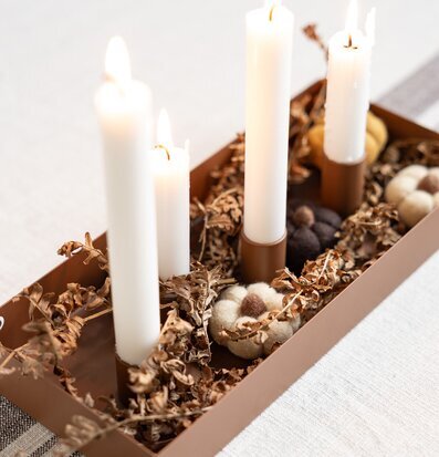Bild med brun ljusstake och naturdekor i jordnära toner