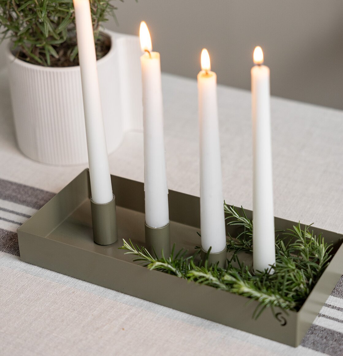 Bild av grön rektangulär ljusstake med naturinslag på bord