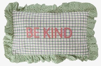 Bild på färgglad prydnadskudde med broderad text och volang