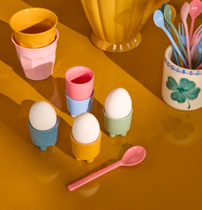 Bild av färgglatt dukat bord med pastellfärgade äggkoppar