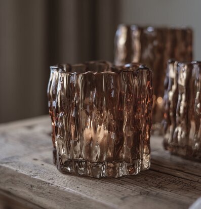 Bild av ljuslykta i kastanjebrunt glas på rustik träyta