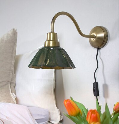 Bild av harmoniskt rum med grön vägglampa och tulpaner