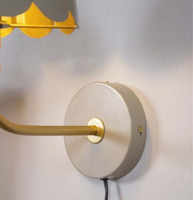 Foto av beige vägglampa med guld och synlig sladd