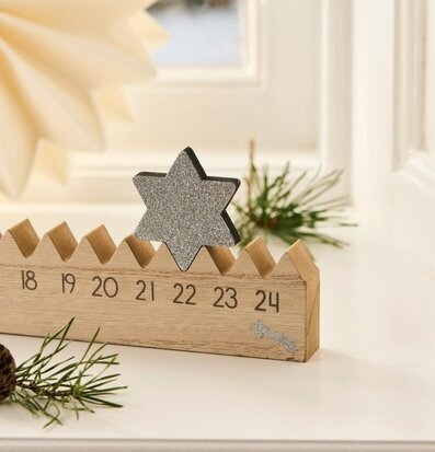 Bild av julkalender i trä med stjärna och vinterdekorationer