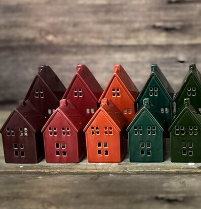 Bild av små keramikhus som ljuslyktor i jordnära färger