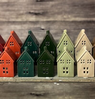 Bild av små keramikhus i olika färger på rustikt träbord