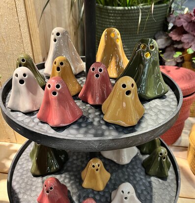 Bild av lekfulla spökfigurer i färg på metallfat med växter