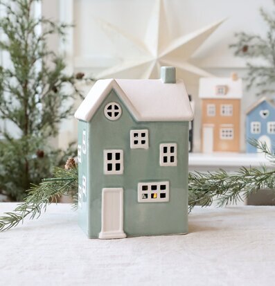 Bild av dekorativ ljuslykta formad som hus i vintermiljö