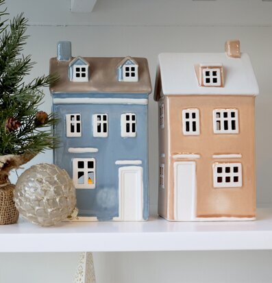 Bild med keramikhus, ljuslykta och vinterdekorationer