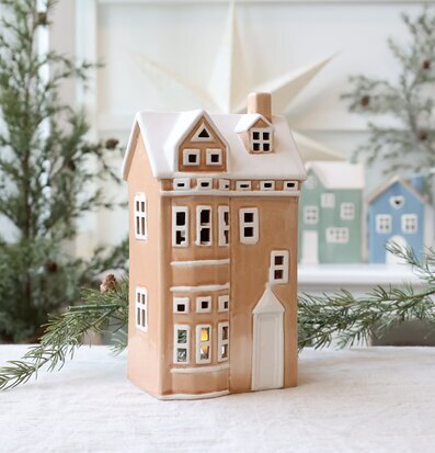 Bild av dekorativt hus i keramik med vintertema och ljus