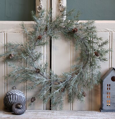 Bild av vinterkrans med kottar och stämningsfull inredning