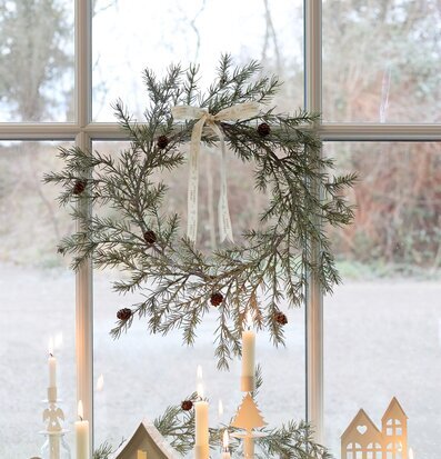 Bild: Vinterfönster med grankrans, småhus och tända ljus