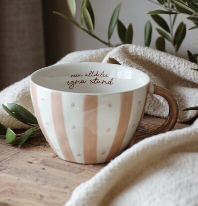 Bild av mugg med text och naturliga inslag på träunderlag