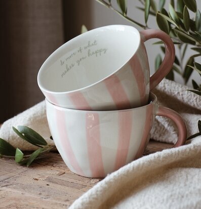 Bild med staplade randiga muggar i rosa och vitt på träbord