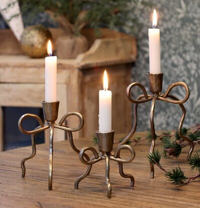 Bild med mässingsljusstakar, juldekoration och träbord